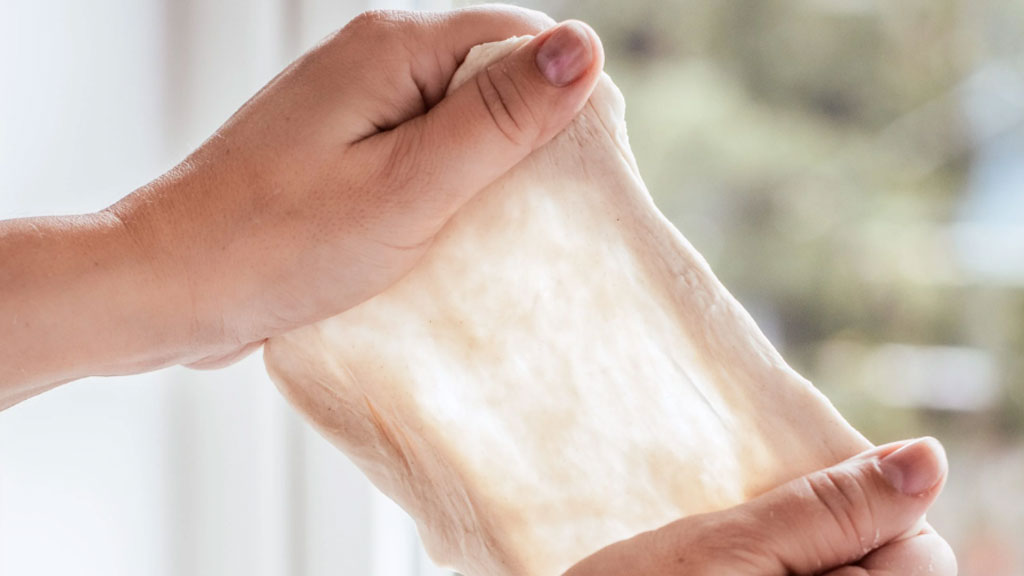 Pâte à pain étirée en membrane translucide démontrant le test du voile